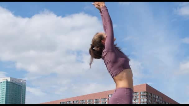 Mujer joven haciendo ejercicios de yoga con la ciudad en el fondo. Respirando. Relax y concepto de libertad . — Vídeo de stock