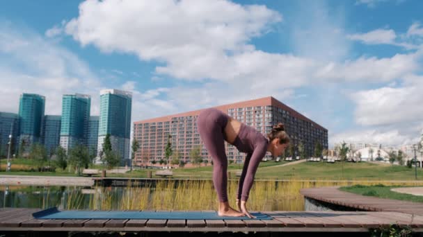 Mujer joven haciendo ejercicios de yoga con la ciudad en el fondo. Relax y concepto de libertad . — Vídeos de Stock