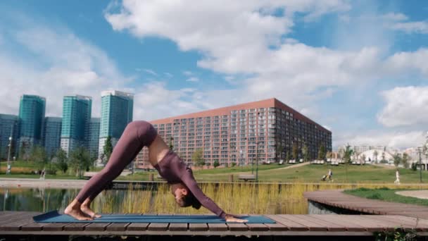 Ung kvinna gör yoga övningar med stad på bakgrunden. Relax och frihets koncept. — Stockvideo