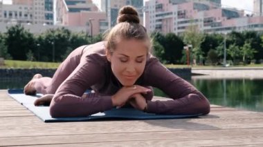 Genç kadın arka planda şehir ile yoga egzersizleri yapıyor. eka pada rajakapotasana. Güvercin pozu