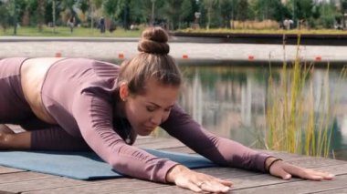 Genç kadın arka planda şehir ile yoga egzersizleri yapıyor. eka pada rajakapotasana. Güvercin pozu