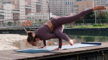 Arka planda şehirle yoga egzersizleri yapan genç bir kadın. eka pada kaundiniasana