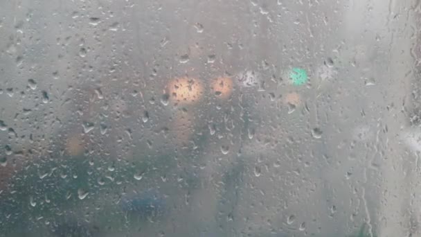 Druppels regen op de achtergrond van blauw glas. Straat Bokeh licht uit focus. — Stockvideo