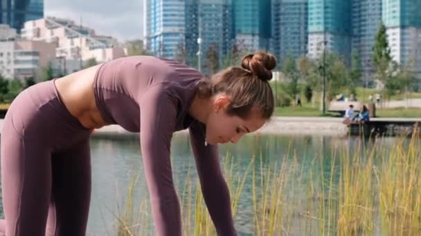 Mujer joven haciendo yoga con la ciudad en el fondo. Ejercicios de vacas y gatos — Vídeos de Stock