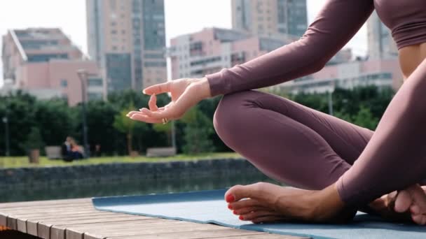 Close up de mãos de mulher yogi sentado na margem do rio na cidade, meditando com os dedos em Jnana mudra — Vídeo de Stock