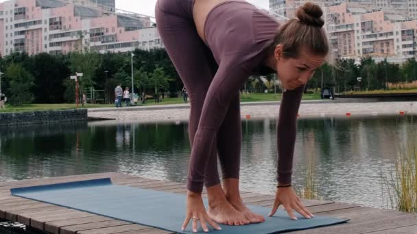 Mujer joven haciendo ejercicios de yoga con la ciudad en el fondo. Surya namaskar — Vídeos de Stock