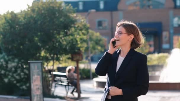 Młoda kobieta biznesu rozmawia na jej telefon komórkowy w budynku biurowym — Wideo stockowe