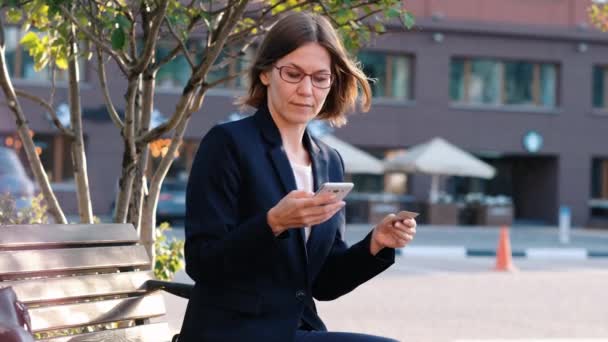 Mulher de negócios jovem pagando wtith cartão de crédito e seu telefone celular, ao ar livre. Pagamento online — Vídeo de Stock