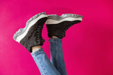 Pembe bir arka plan üzerinde markasız modern sportif ayakkabı kadın ayakları.