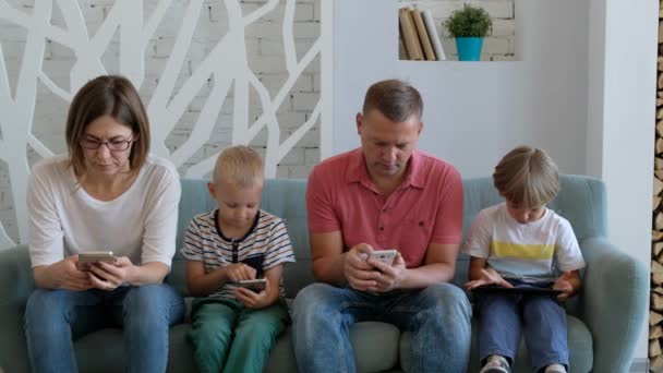 I genitori e i bambini della famiglia dipendenti dai dispositivi usano il telefono tablet seduto su un divano a casa — Video Stock