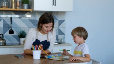 Anne oğlunun mutfak odasında ev ödevi yapmasına yardım etti. Aile, yaşam tarzı ve eğitim anlayışıolan kişiler.
