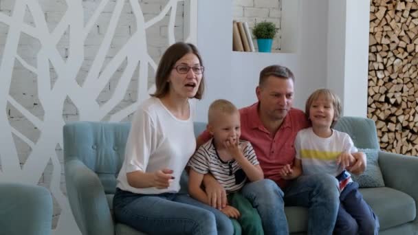 Upphetsad familj fotbollsfans tittar på TV, firar mål tillsammans, lyckliga föräldrar mamma pappa och små barn som stöder favoritfotbollslag seger hemma sitta på soffan — Stockvideo