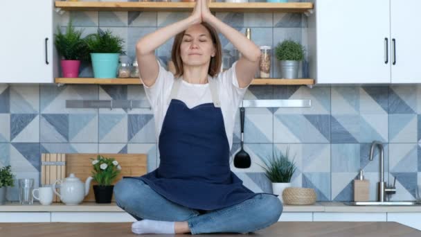 Ung attraktiv kvinna sittande yoga asana pose i köket på morgonen, mediterar — Stockvideo