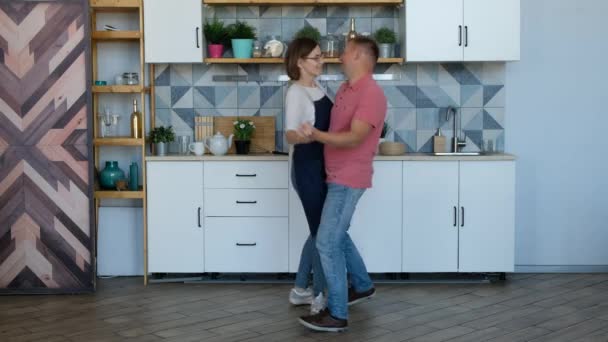 Feliz joven pareja recién casada bailando escuchando música en la cocina en casa enamorada divirtiéndose — Vídeo de stock