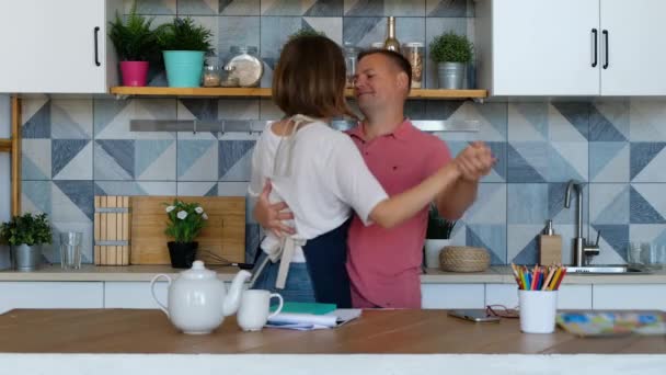 幸せなカップルは、楽しみを持って愛の自宅でキッチンで音楽を聴いて踊って新婚 — ストック動画