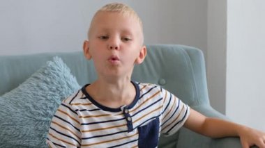 Küçük çocuk öksürüyor, oturma odasında kanepede oturuyor.