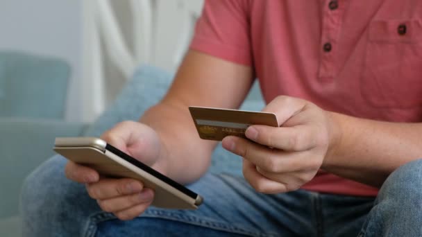 Молодой кавказский мужчина использует смартфон для покупок через интернет с кредитной картой в гостиной . . — стоковое видео