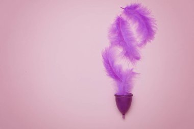 Pembe arka planda tüy olan adet kupası, gezegenin kadın sağlığı ve ekolojisi kavramı