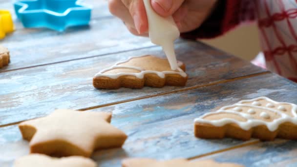 Hacer galletas de jengibre para Navidad. Pintura a mano para mujer con esmalte blanco en galletas — Vídeos de Stock