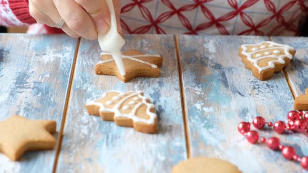 Hacer galletas de jengibre para Navidad. Pintura a mano para mujer con esmalte blanco en galletas — Vídeo de stock