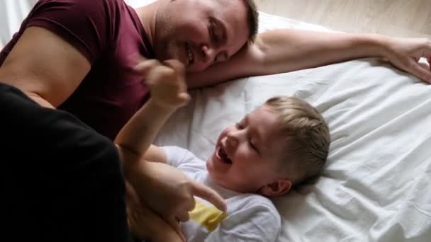 행복 한 아버지와아 들 이 침대에서 웃으면서 재미있게 놀고 있다. 위에서 바라본 경관 — 비디오