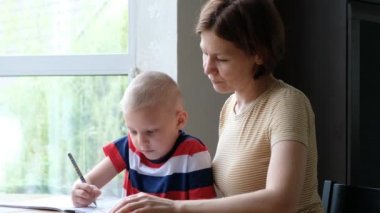 Anne, küçük oğlunun evde ödevlerini yapmasına yardım ediyor.