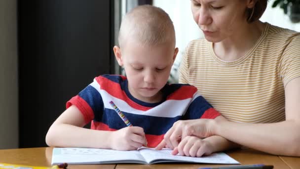 Mor hjälper sitt lilla barn att göra läxor inomhus — Stockvideo