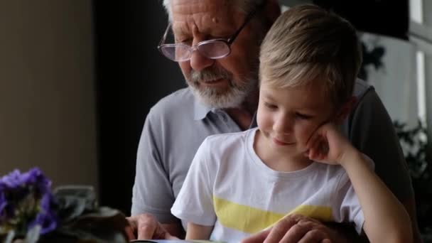 Abuelo hombre mayor leyendo un libro con su nieto — Vídeo de stock