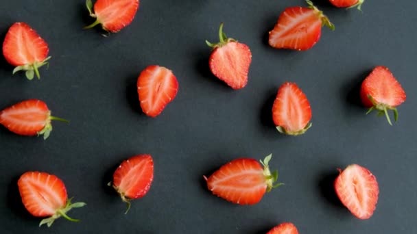 Schwarzer, drehbarer Hintergrund mit Erdbeerhälften, Draufsicht — Stockvideo
