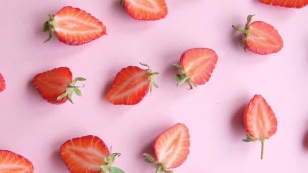 Pink rotating background with juicy strawberry halves, top view — Stock Video