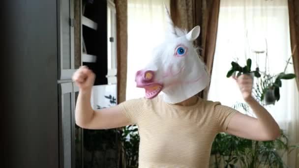 Rolig konstig video - kvinna som dansar i enhörning mask huvud hemma — Stockvideo