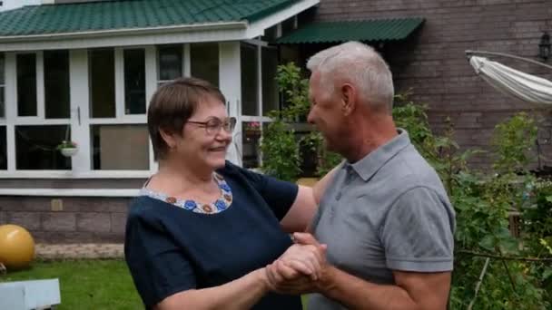 Casal idoso feliz - homem e mulher - dançando e rindo do lado de fora por sua casa — Vídeo de Stock