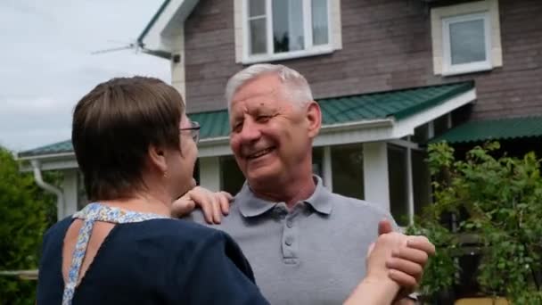 Casal idoso feliz - homem e mulher - dançando e rindo do lado de fora por sua casa — Vídeo de Stock