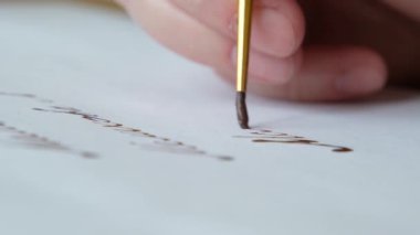 Fırça darbesiyle beyaz kağıda çizgiler çiziliyor