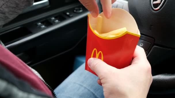 MOSCOW, RÚSSIA - MAIO 2020: Um homem come uma batata frita francesa de McDonalds sentado em um carro — Vídeo de Stock