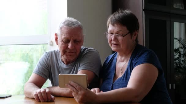 Ευτυχισμένο ηλικιωμένο ζευγάρι κρατά έξυπνο τηλέφωνο και μιλάει μέσω φωνητικής κλήσης, κοιτάζοντας web camera — Αρχείο Βίντεο