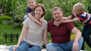 Aile fotoğrafı - kadın, erkek ve çocukları açık havada güneşli bir günün tadını çıkarıyorlar.