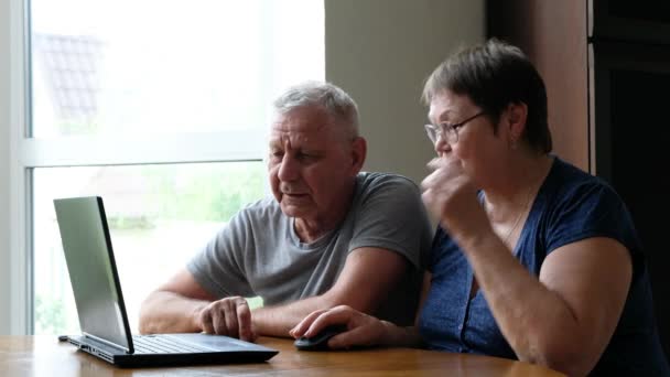 Casal sênior em casa usando laptop. Família aposentada trabalhando na aprendizagem de computadores mídias sociais . — Vídeo de Stock