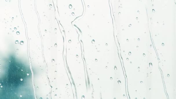 Primer plano de gotas de lluvia de agua en el cristal de la ventana. Grandes gotas de lluvia y flujos golpean un cristal de ventana durante una ducha de verano . — Vídeos de Stock