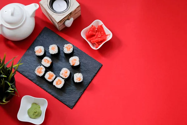 Encomende rolos de sushi de comida japonesa enquanto você fica em casa em quarentena. Forma da casa no fundo vermelho com espaço de cópia Imagens De Bancos De Imagens