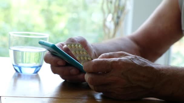 Hombre mayor sosteniendo unas pastillas y un smartphone, de cerca. Pedir medicamentos en línea — Vídeo de stock