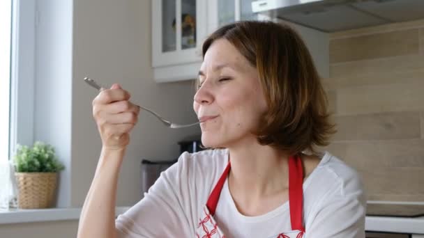 Vrouw probeert heerlijke schotel in de keuken — Stockvideo