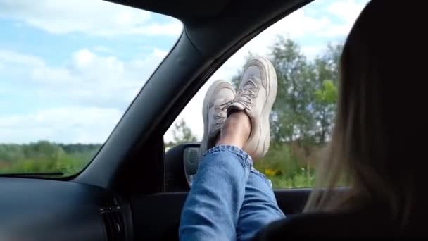 Uma jovem mulher livre gosta de viajar em um carro, saindo de suas pernas em uma janela aberta. Liberdade verão copcept — Vídeo de Stock