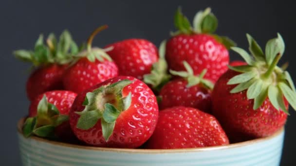 Verse biologische aardbei in een ronddraaiende kom. close-up, slow motion, donkere achtergrond — Stockvideo