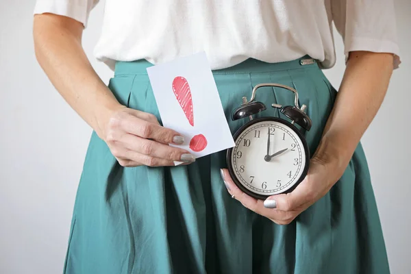 Mulher segurando relógio na barriga. Perdeu o período, gravidez indesejada e atraso na menstruação. Imagens De Bancos De Imagens