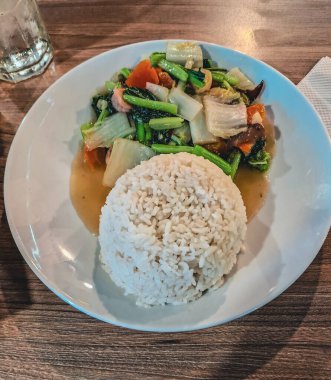 tavuklu pilav ve sebzeler ahşap bir masada.