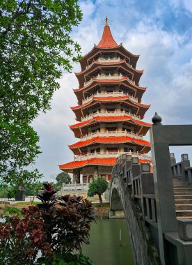 Kırmızı kıvrımlı çatıları olan geleneksel Çin tarzı pagoda canlı mavi bir gökyüzünün altında duruyor.