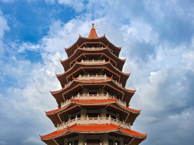 Kırmızı kıvrımlı çatıları olan geleneksel Çin tarzı pagoda canlı mavi bir gökyüzünün altında duruyor.