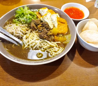 asian noodles soup with pork and egg, fried noodles and vegetables in the bowl