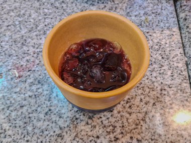 a cup of coffee with ice cubes on the table